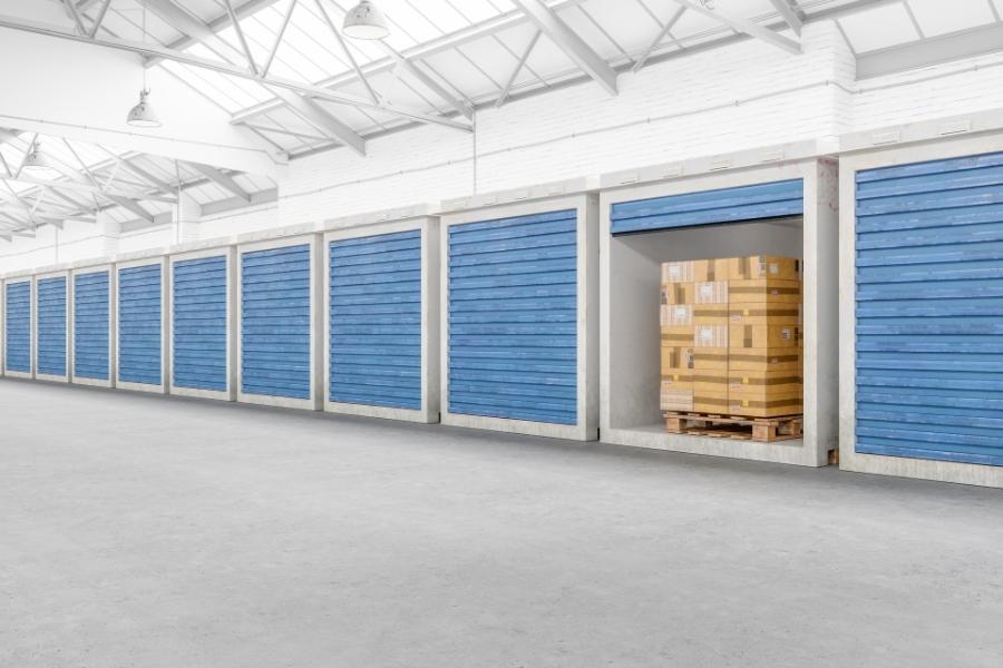 Plusieurs unités de stockage alignées dans un entrepôt moderne avec une porte ouverte laissant voir des cartons.