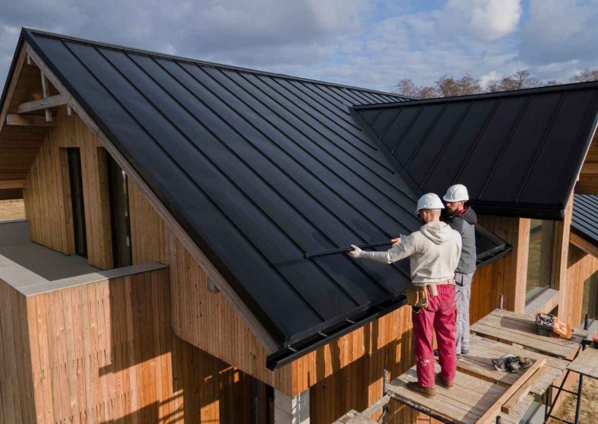 Ouvriers installant un toit noir sur une maison en bois en cours de construction.