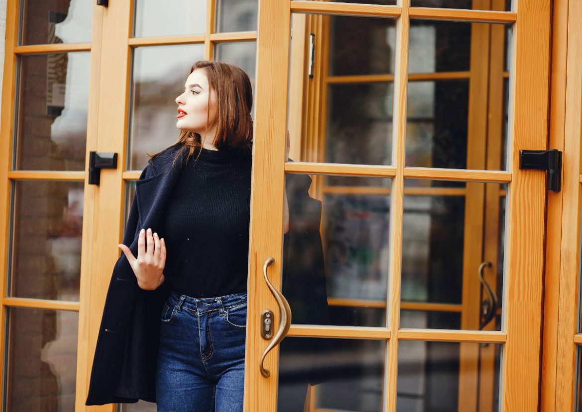 Femme sortant d’une porte d’entrée vitrée en bois clair. Femme élégante sortant d'une porte d'entrée vitrée.