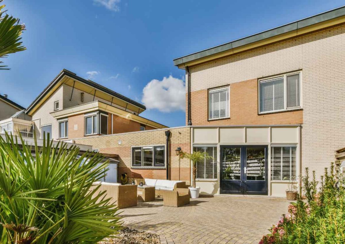 Maison neuve : Cour arrière aménagée avec mobilier d'extérieur et un revêtement de sol en briques.