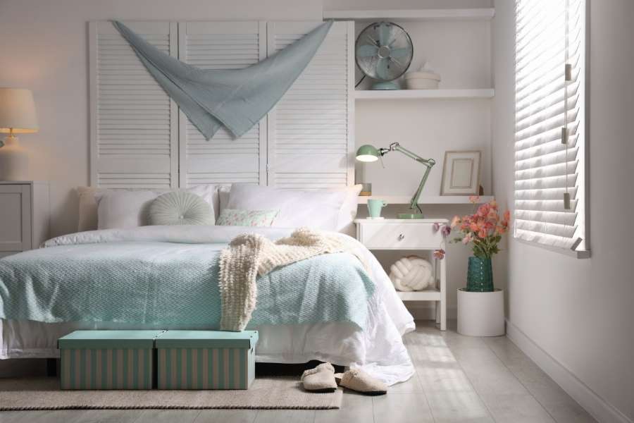Une chambre claire et bien rangée pour optimiser l'espace dans un petit appartement avec des boîtes de rangement sous le lit et des étagères murales.