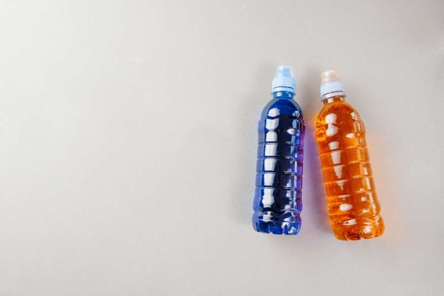 Deux bouteilles de sport contenant de l'eau de mer isotonique colorée sur un fond neutre.