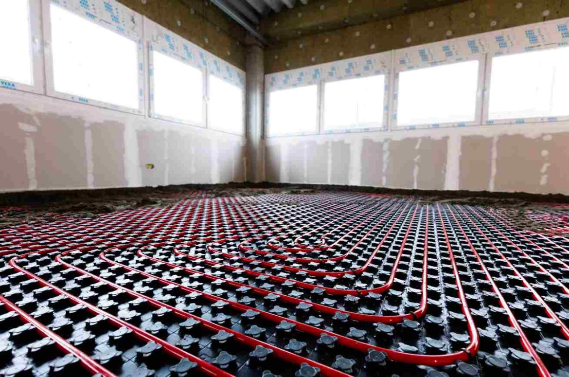Installation de tuyaux de plancher chauffant sur des panneaux à plots dans une pièce en construction, un élément clé pour estimer le prix installation chauffage au sol maison neuve.