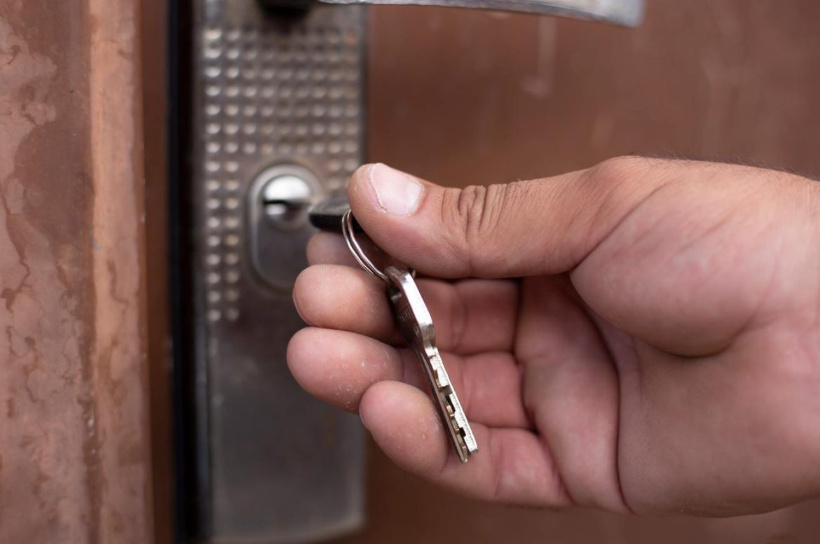 Une main insère une clé dans la serrure d'une porte nécessitant l'intervention d'un serrurier paris urgence nuit pas cher.
