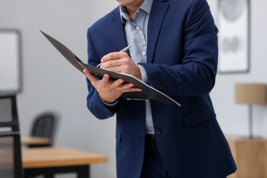 Un professionnel en costume prend des notes sur un dossier pour une estimation en ligne.